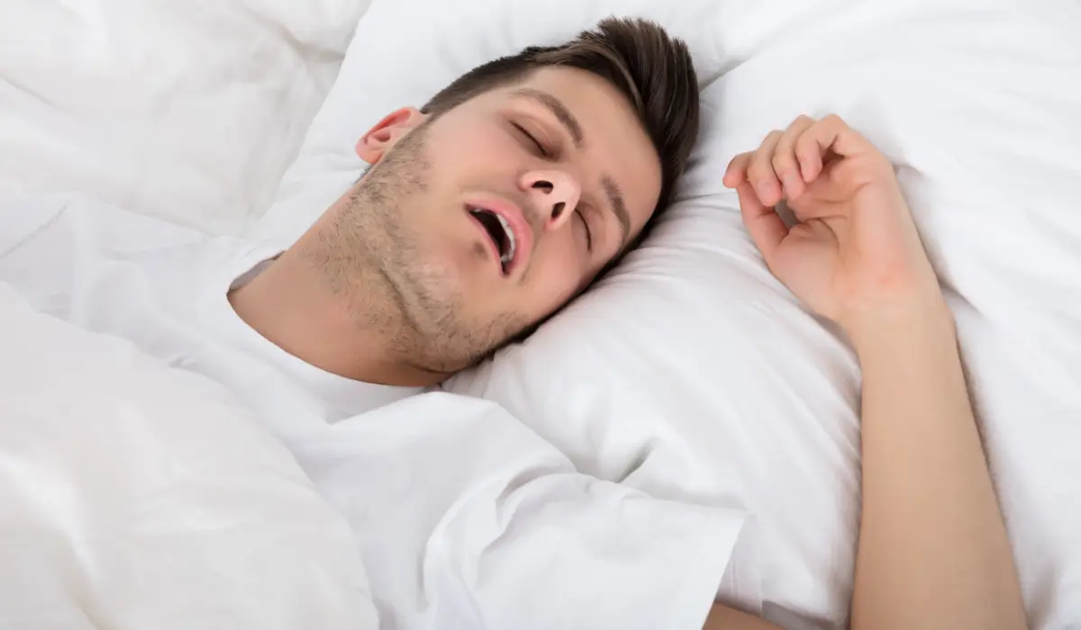 Man sleeping with open mouth showing possible sleep apnea signs linked to nighttime breathing obstruction.