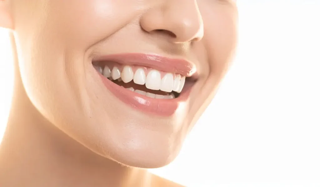 Close-up of natural bright teeth whitening result on smiling woman with healthy gums and smooth enamel.