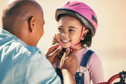Parent helping child Protect Your Child’s Teeth before cycling using helmet, healthy habits, and supervision together.